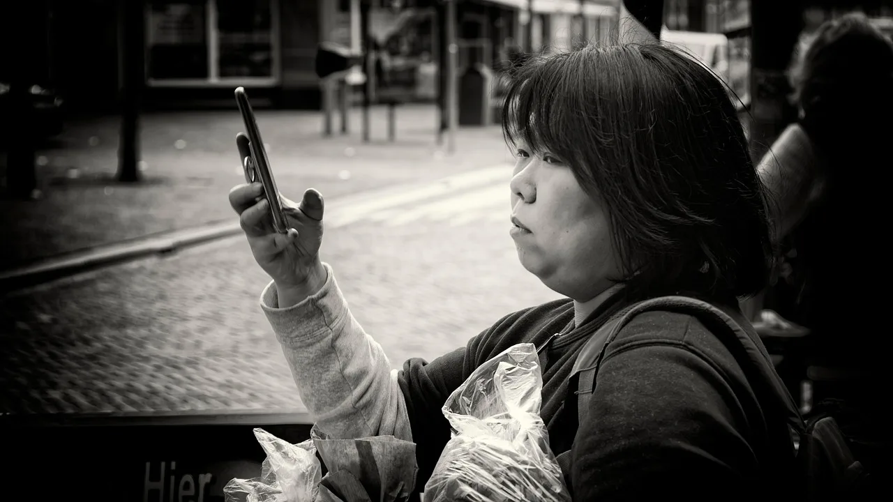 woman, mobile phone, street photography, black and white, video call, portrait. Verifying a catfishing suspicion before you meet anyone in person