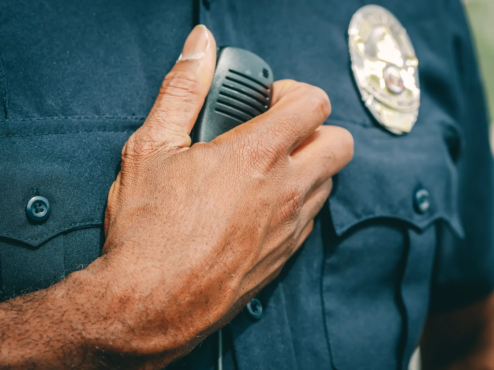 A police officer in uniform holding a radio communicator, showcasing professional authority. Impersonation Scams: Verify Others, Protect Your Name