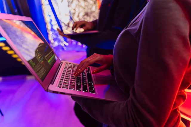 Two professionals analyzing data on laptops with colorful lighting, focusing on cybersecurity details. Free tools versus paid services for a privacy checkup